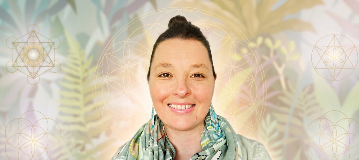 Leah May smiling with her hair in a bun wears a light green patterned scarf and matching top, set against a soft, decorative background of botanical leaves and geometric symbols.